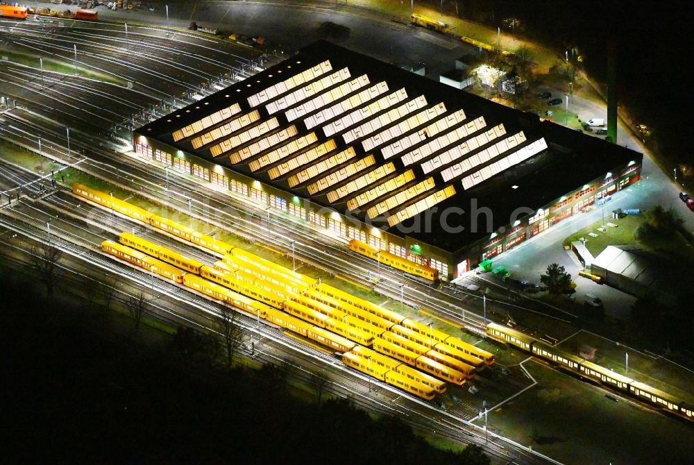 Aerial image at night Berlin - Night lighting Railway depot and repair shop for maintenance and repair of trains of passenger transport of the series of U-Bahn - Betriebswerkstatt BVG on Schlosserweg in the district Neukoelln in Berlin, Germany