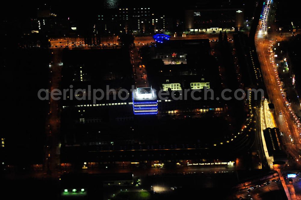 Berlin at night from above - Nachtaufnahme: Oberbaum-City, das Gelände der ehemaligen Narva Lampenfabrik, in Berlin-Friedrichshain zwischen U-Bahnhof und S-Bahnhof Warschauer Straße. Das markanteste Bauwerk ist der Narva-Turm, das erste Hochhaus von Berlin, daneben die U-Bahn-Abstellanlage entlang der Rudolfstraße. Night Shot: Oberbaum City in Berlin-Friedrichshain with the Narva-Tower, the first tower building of Berlin. Next to it the storage siding of Berlin subway along the street Rudolfstrasse.