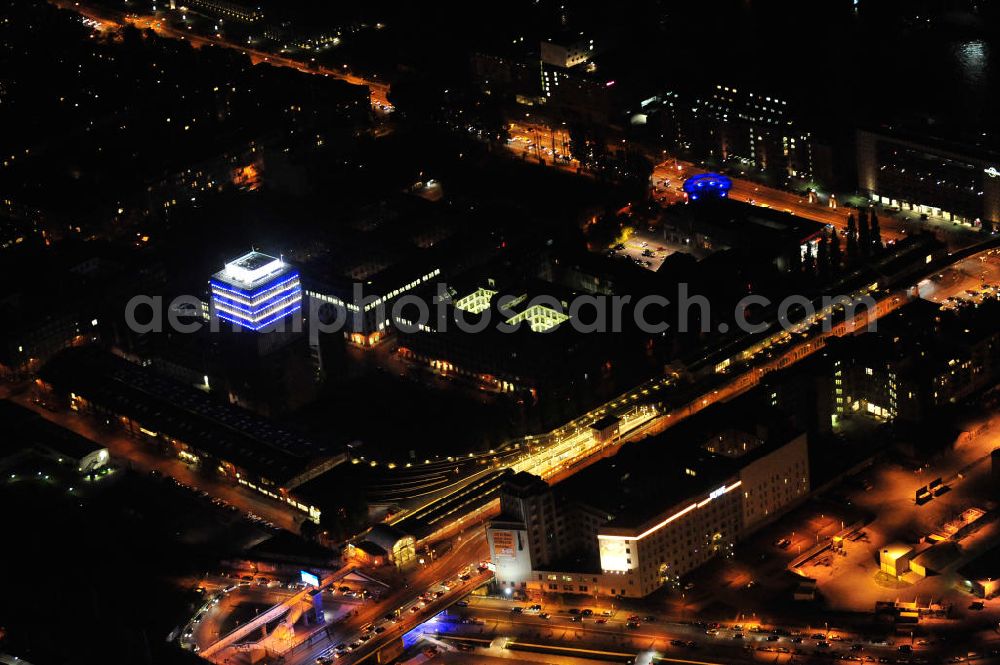 Aerial photograph at night Berlin - Nachtaufnahme: Oberbaum-City, das Gelände der ehemaligen Narva Lampenfabrik, in Berlin-Friedrichshain zwischen U-Bahnhof und S-Bahnhof Warschauer Straße. Das markanteste Bauwerk ist der Narva-Turm, das erste Hochhaus von Berlin, daneben die U-Bahn-Abstellanlage entlang der Rudolfstraße. Night Shot: Oberbaum City in Berlin-Friedrichshain with the Narva-Tower, the first tower building of Berlin. Next to it the storage siding of Berlin subway along the street Rudolfstrasse.