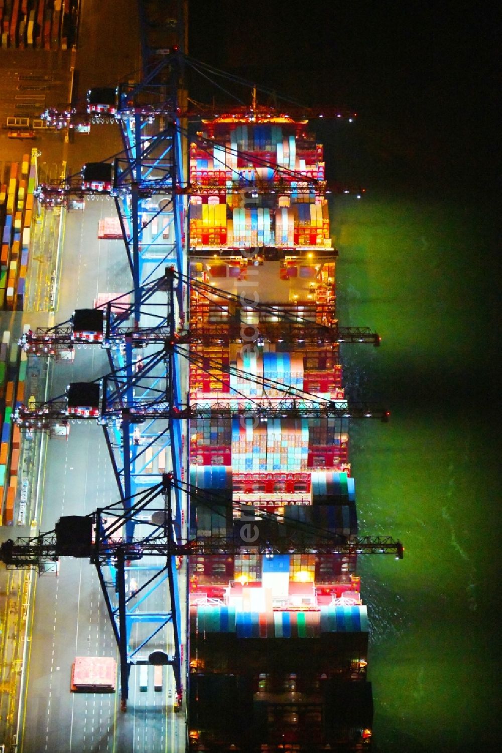 Hamburg at night from the bird perspective: Night lighting container ship on den HHLA Container Terminal Tollerort Am Vulkonhafen in the port in the district Steinwerder in Hamburg, Germany