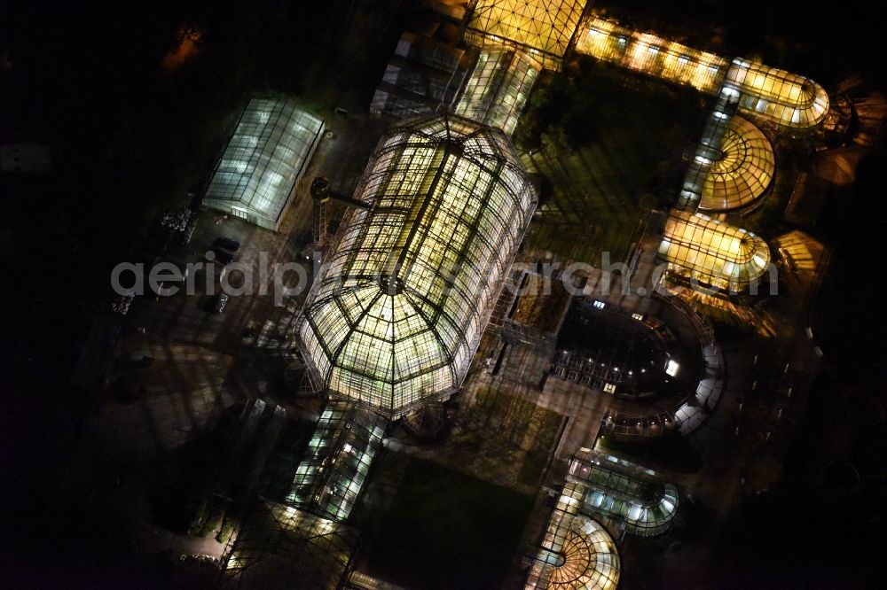 Aerial image at night Berlin - Main building and greenhouse complex of the Botanical Gardens Berlin-Dahlem in Berlin. The historical glass buildings and greenhouses are dedicated to different areas. The Large Tropical House and the Victoria-House are located in the center