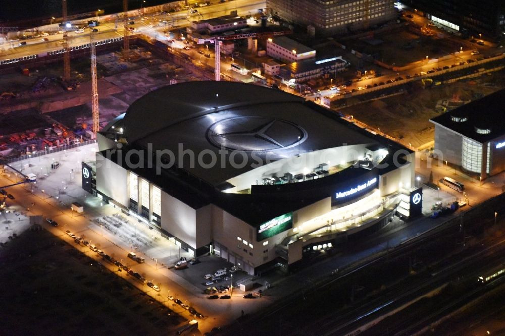 Aerial photograph at night Berlin - Night view of Mercedes-Benz-Arena on the Spree riverbank in the Friedrichshain part of Berlin. The former O2 World - now Mercedes-Benz-Arena - is located in the Anschutz Areal, a business and office space on the riverbank