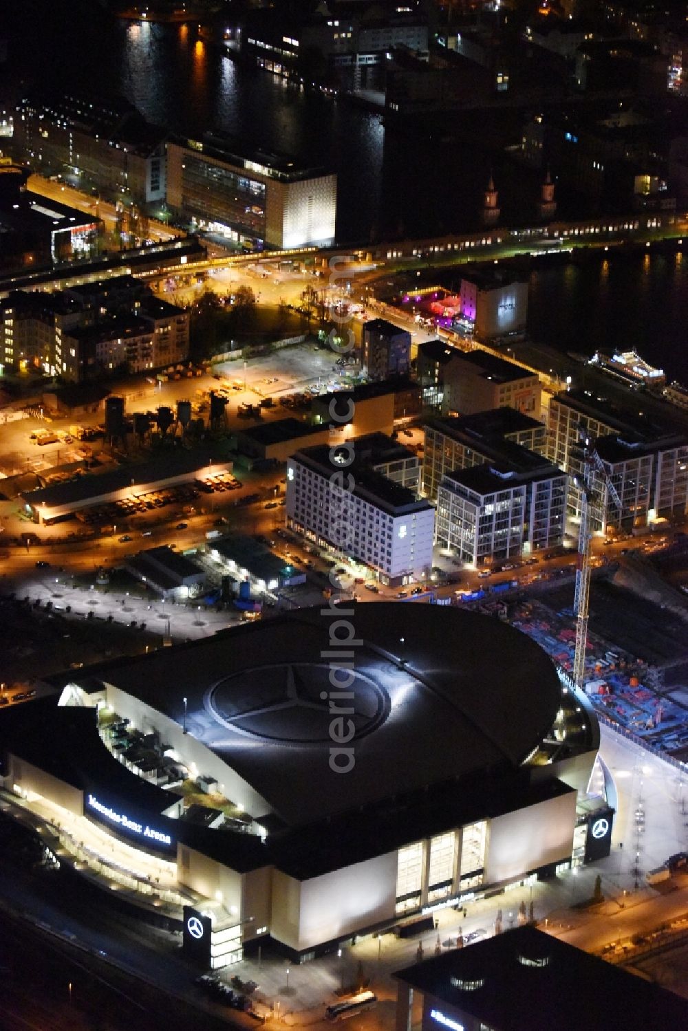 Berlin at night from above - Night view of Mercedes-Benz-Arena on the Spree riverbank in the Friedrichshain part of Berlin. The former O2 World - now Mercedes-Benz-Arena - is located in the Anschutz Areal, a business and office space on the riverbank