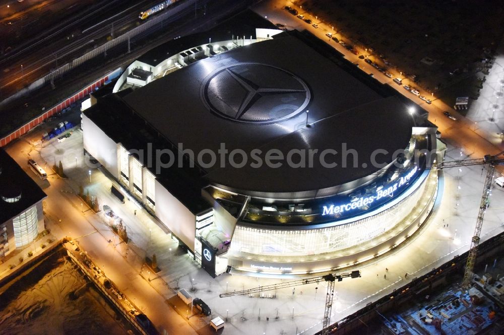 Berlin at night from the bird perspective: Night view of Mercedes-Benz-Arena on the Spree riverbank in the Friedrichshain part of Berlin. The former O2 World - now Mercedes-Benz-Arena - is located in the Anschutz Areal, a business and office space on the riverbank