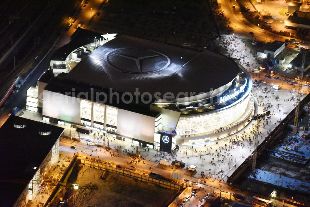 Berlin at night from the bird perspective: Night view of Mercedes-Benz-Arena on the Spree riverbank in the Friedrichshain part of Berlin. The former O2 World - now Mercedes-Benz-Arena - is located in the Anschutz Areal, a business and office space on the riverbank