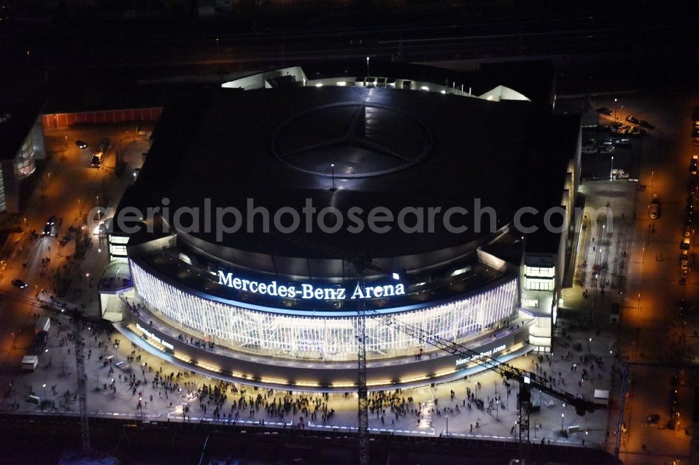 Berlin at night from the bird perspective: Night view of Mercedes-Benz-Arena on the Spree riverbank in the Friedrichshain part of Berlin. The former O2 World - now Mercedes-Benz-Arena - is located in the Anschutz Areal, a business and office space on the riverbank