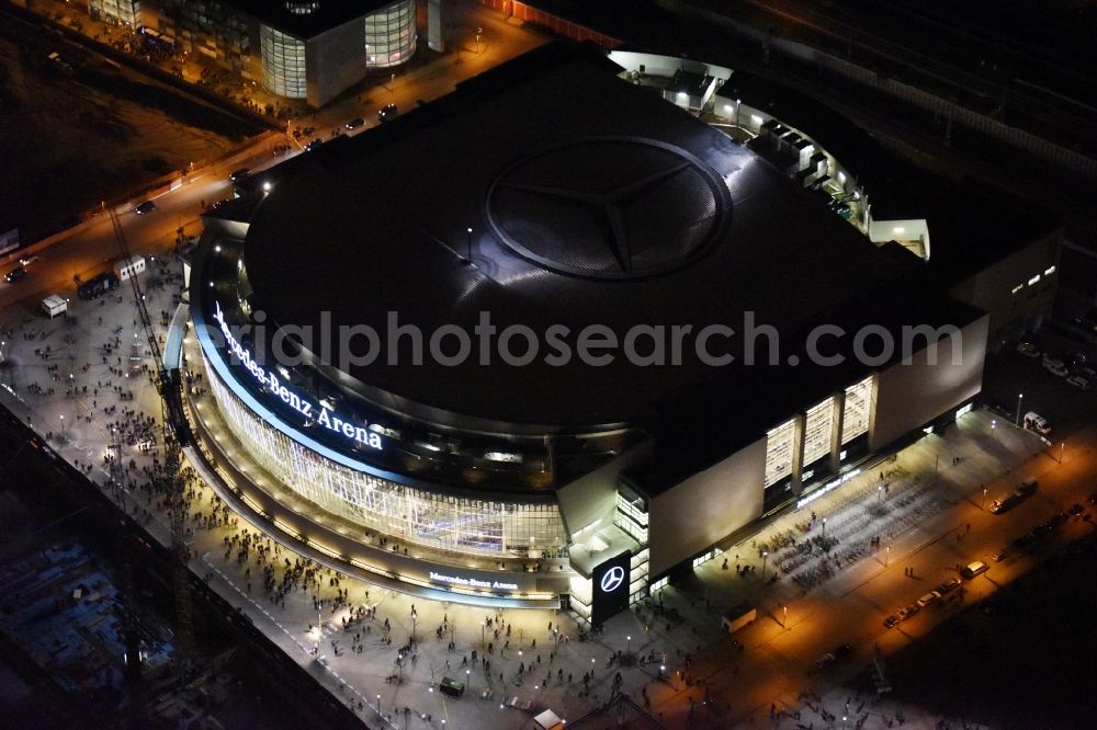 Aerial photograph at night Berlin - Night view of Mercedes-Benz-Arena on the Spree riverbank in the Friedrichshain part of Berlin. The former O2 World - now Mercedes-Benz-Arena - is located in the Anschutz Areal, a business and office space on the riverbank