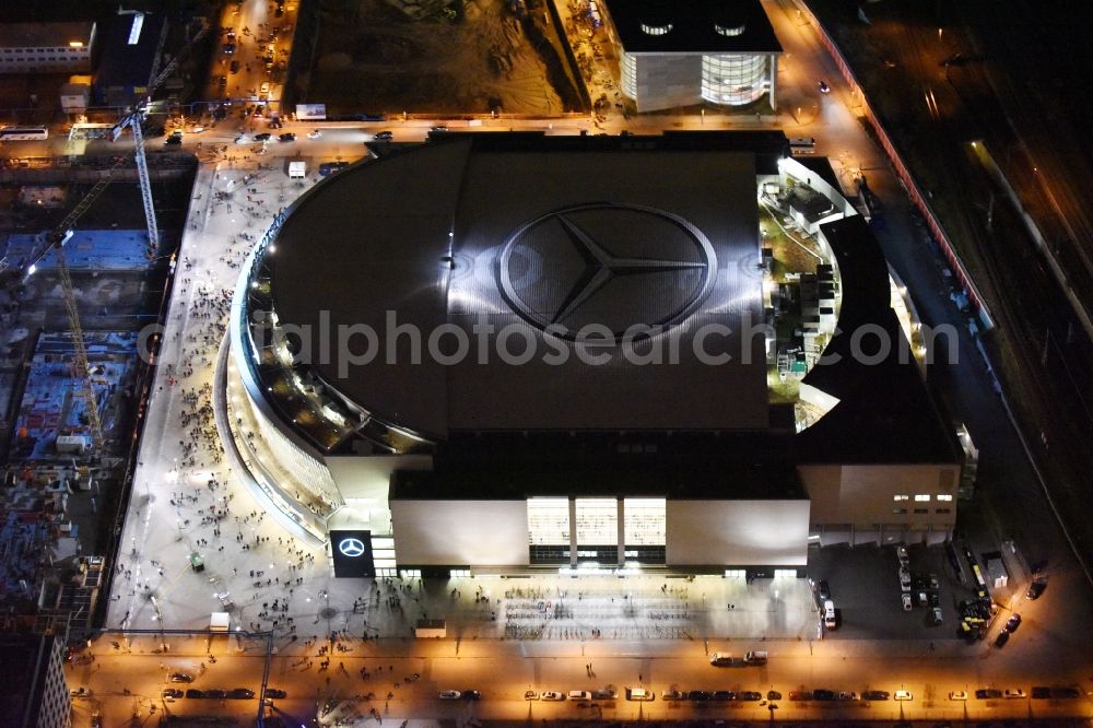 Aerial image at night Berlin - Night view of Mercedes-Benz-Arena on the Spree riverbank in the Friedrichshain part of Berlin. The former O2 World - now Mercedes-Benz-Arena - is located in the Anschutz Areal, a business and office space on the riverbank