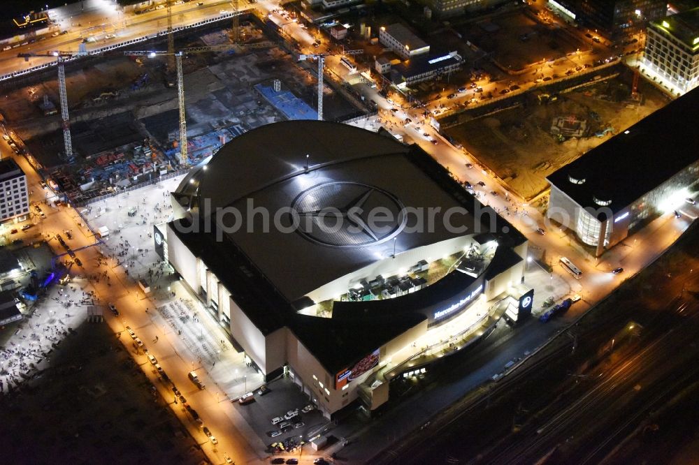 Berlin at night from the bird perspective: Night view of Mercedes-Benz-Arena on the Spree riverbank in the Friedrichshain part of Berlin. The former O2 World - now Mercedes-Benz-Arena - is located in the Anschutz Areal, a business and office space on the riverbank