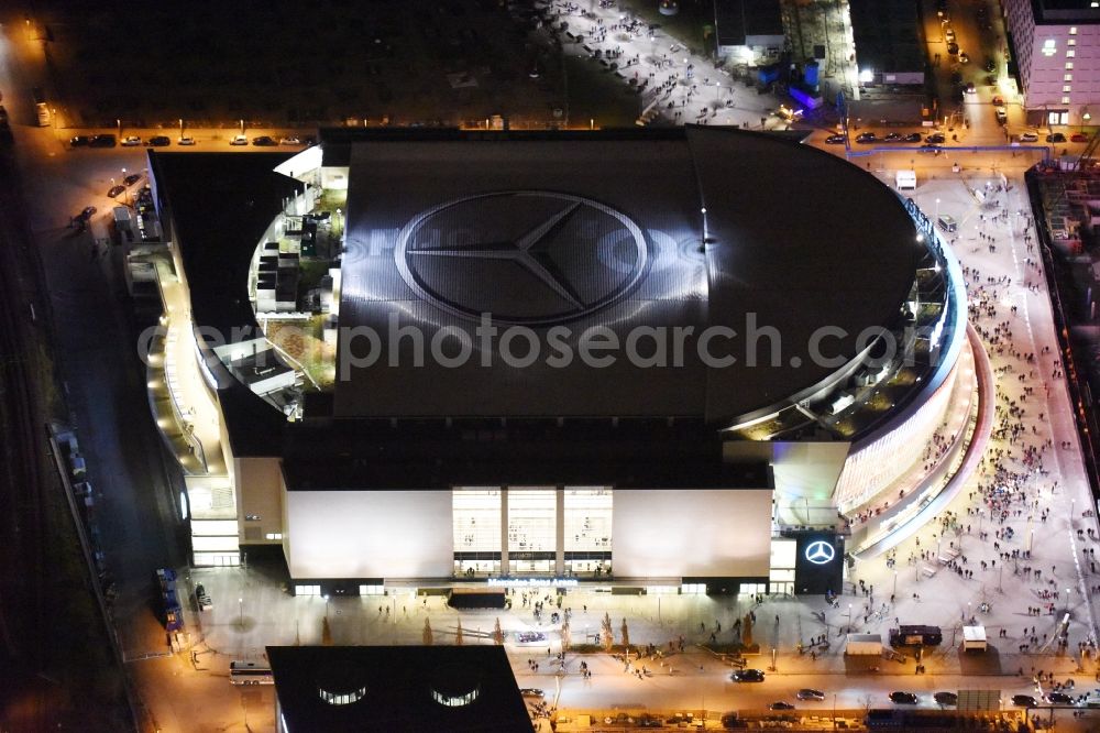 Aerial image at night Berlin - Night view of Mercedes-Benz-Arena on the Spree riverbank in the Friedrichshain part of Berlin. The former O2 World - now Mercedes-Benz-Arena - is located in the Anschutz Areal, a business and office space on the riverbank