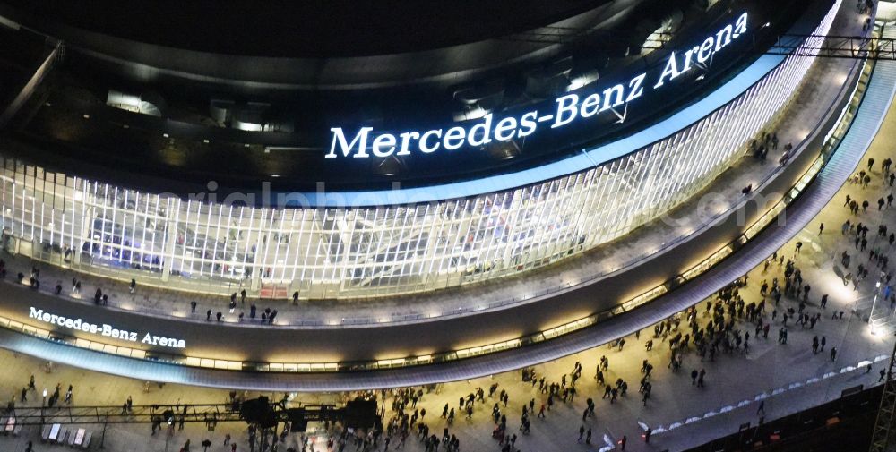 Aerial image at night Berlin - Night view of Mercedes-Benz-Arena on the Spree riverbank in the Friedrichshain part of Berlin. The former O2 World - now Mercedes-Benz-Arena - is located in the Anschutz Areal, a business and office space on the riverbank