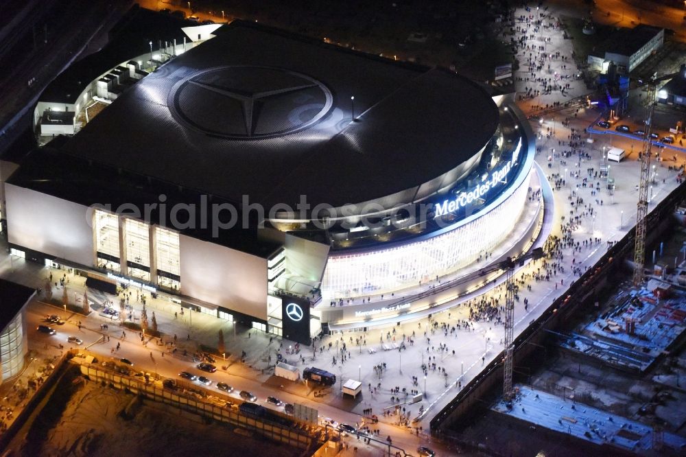 Aerial image at night Berlin - Night view of Mercedes-Benz-Arena on the Spree riverbank in the Friedrichshain part of Berlin. The former O2 World - now Mercedes-Benz-Arena - is located in the Anschutz Areal, a business and office space on the riverbank