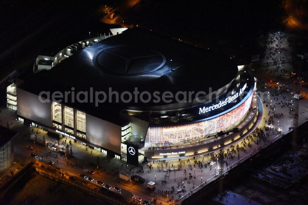 Berlin at night from the bird perspective: Night view of Mercedes-Benz-Arena on the Spree riverbank in the Friedrichshain part of Berlin. The former O2 World - now Mercedes-Benz-Arena - is located in the Anschutz Areal, a business and office space on the riverbank