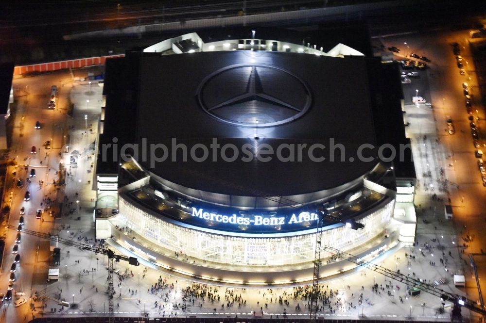 Aerial image at night Berlin - Night view of Mercedes-Benz-Arena on the Spree riverbank in the Friedrichshain part of Berlin. The former O2 World - now Mercedes-Benz-Arena - is located in the Anschutz Areal, a business and office space on the riverbank