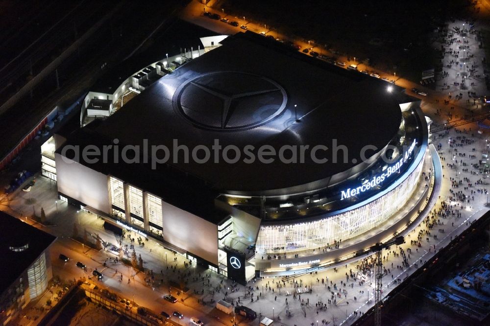 Aerial photograph at night Berlin - Night view of Mercedes-Benz-Arena on the Spree riverbank in the Friedrichshain part of Berlin. The former O2 World - now Mercedes-Benz-Arena - is located in the Anschutz Areal, a business and office space on the riverbank