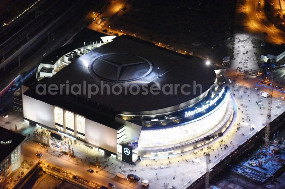 Aerial image at night Berlin - Night view of Mercedes-Benz-Arena on the Spree riverbank in the Friedrichshain part of Berlin. The former O2 World - now Mercedes-Benz-Arena - is located in the Anschutz Areal, a business and office space on the riverbank