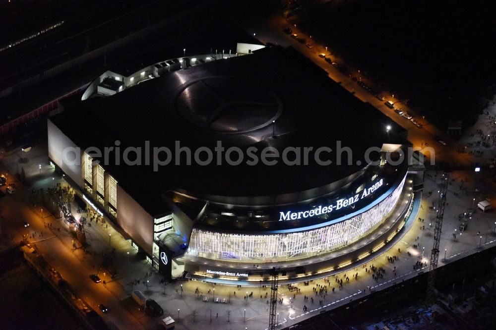 Berlin at night from the bird perspective: Night view of Mercedes-Benz-Arena on the Spree riverbank in the Friedrichshain part of Berlin. The former O2 World - now Mercedes-Benz-Arena - is located in the Anschutz Areal, a business and office space on the riverbank