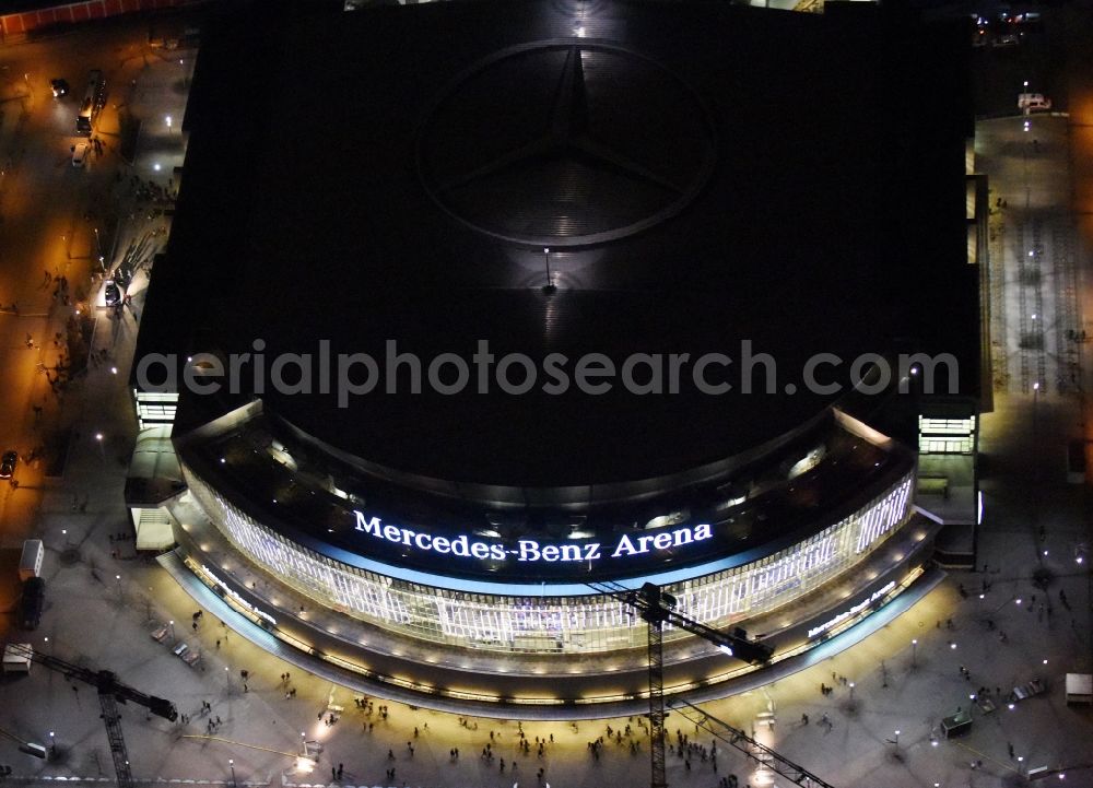 Berlin at night from the bird perspective: Night view of Mercedes-Benz-Arena on the Spree riverbank in the Friedrichshain part of Berlin. The former O2 World - now Mercedes-Benz-Arena - is located in the Anschutz Areal, a business and office space on the riverbank