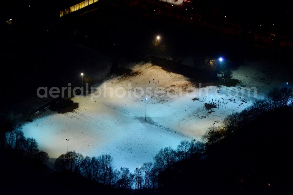 München at night from the bird perspective: Night aerial of the illuminated and snow covered sports ground Ramersdorf in Munich in Bavaria