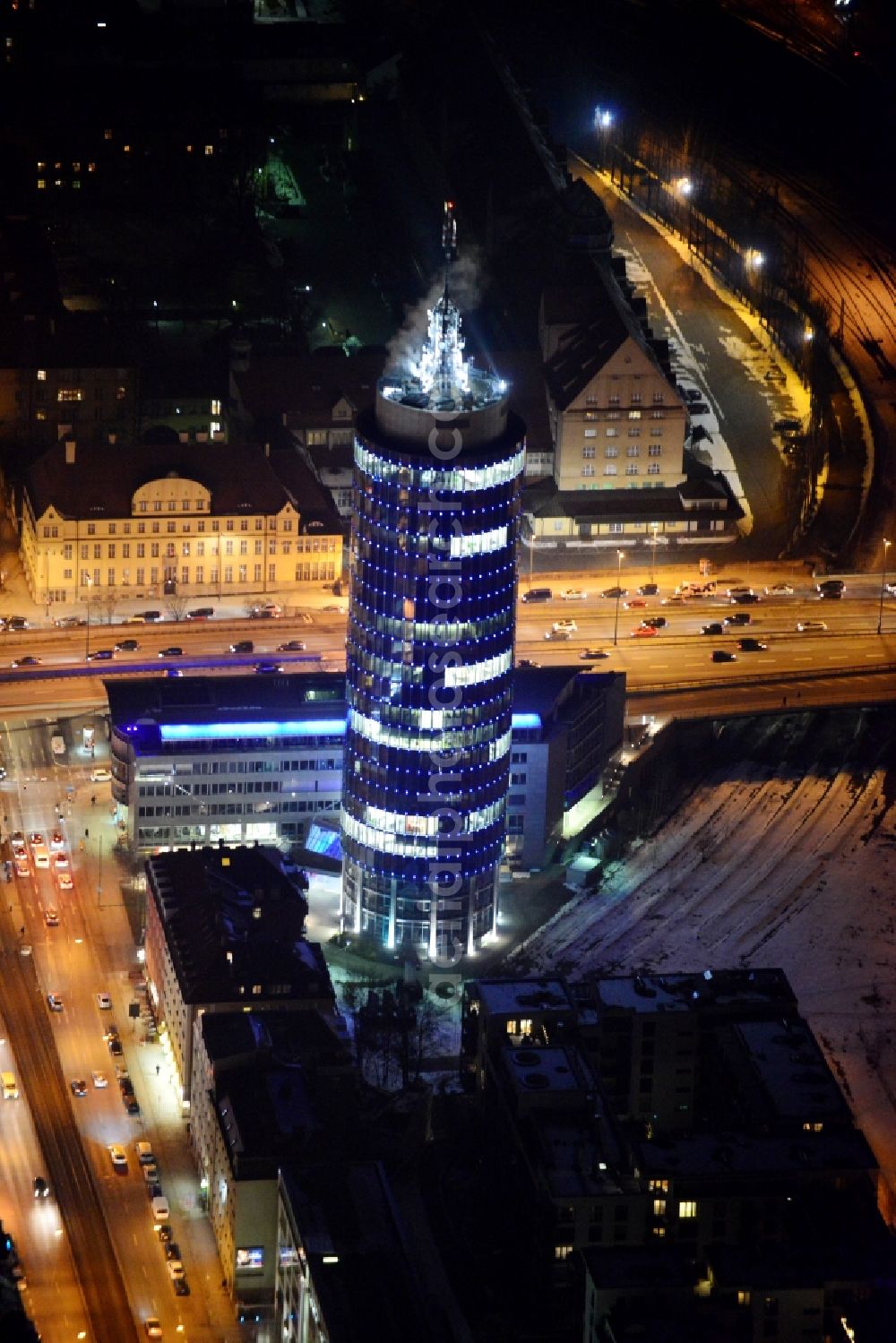 München at night from the bird perspective: Night aerial view of the blue illuminated skyscraper Central Tower in Munich in Bavaria