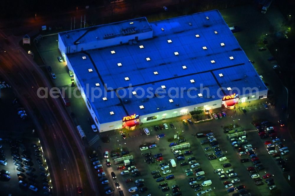 Aerial image at night Neuruppin - Night lighting Building of the shopping center of real GmbH on Babimost- Ring in Neuruppin in the state Brandenburg, Germany