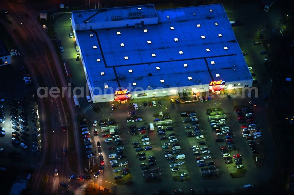 Neuruppin at night from above - Night lighting Building of the shopping center of real GmbH on Babimost- Ring in Neuruppin in the state Brandenburg, Germany