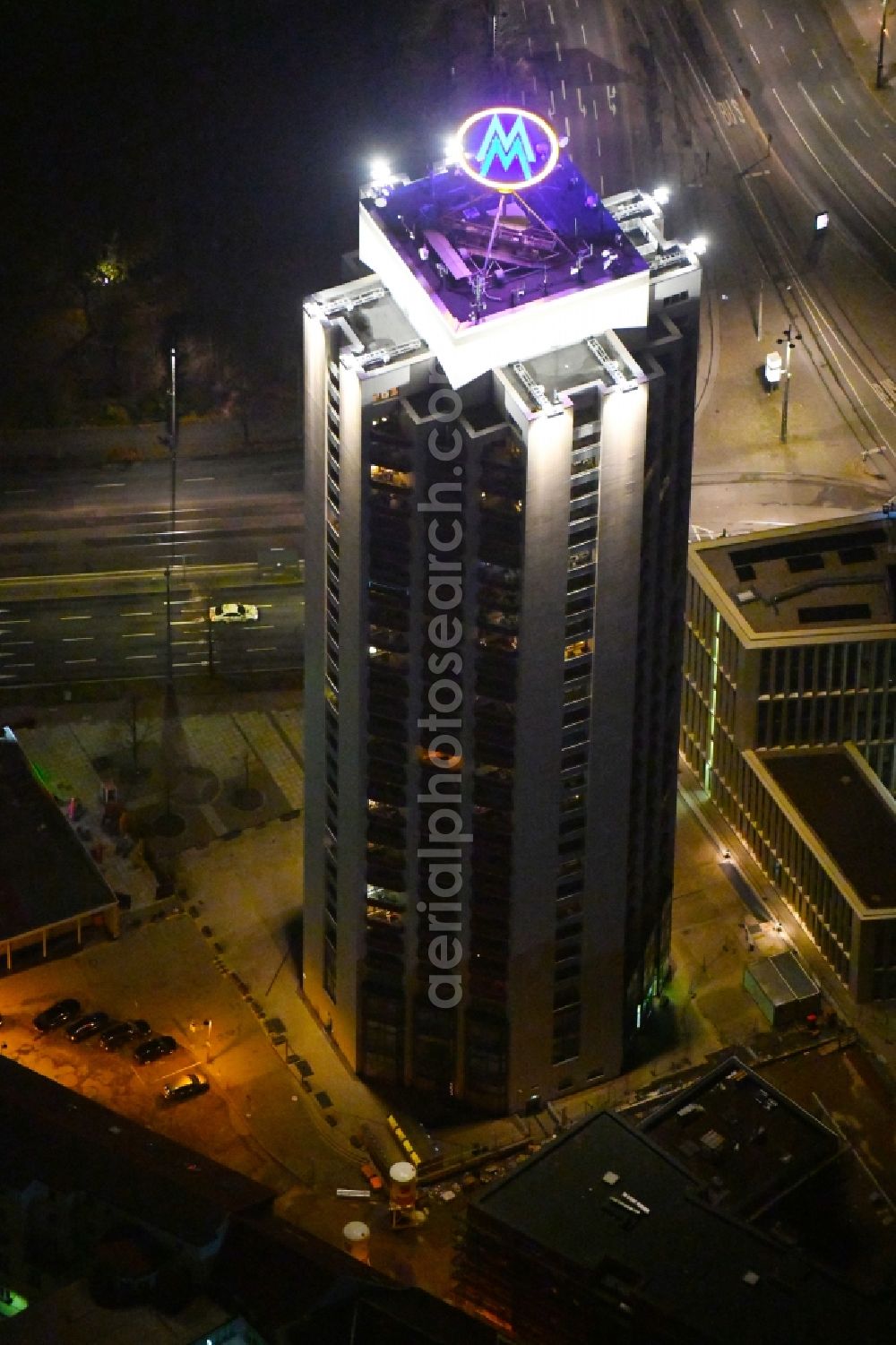 Aerial photograph at night Leipzig - Night lighting the fair logotype neon sign on the roof of the High-Rise building complex of the headquarters of the Leipziger Wohnungs- und Baugesellschaft (LWB) on Wintergartenhochhaus - skyscraper in Leipzig in Saxony