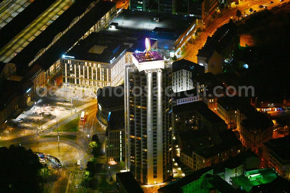 Leipzig at night from the bird perspective: Night lighting the fair logotype neon sign on the roof of the High-Rise building complex of the headquarters of the Leipziger Wohnungs- und Baugesellschaft (LWB) on Wintergartenhochhaus - skyscraper in Leipzig in Saxony