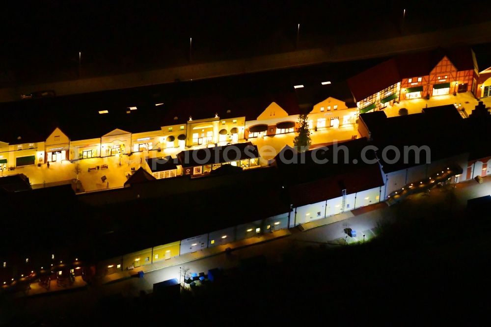 Wustermark at night from the bird perspective: Night lighting building of the shopping center Designer Outlet Berlin in Wustermark in the state Brandenburg, Germany