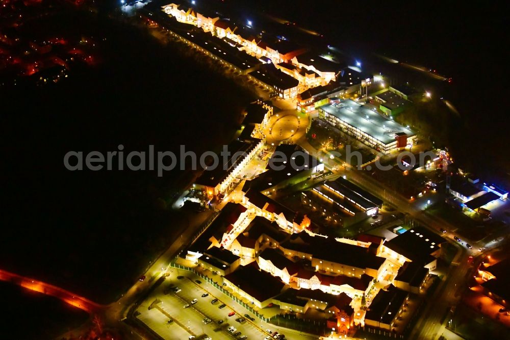 Wustermark at night from the bird perspective: Night lighting building of the shopping center Designer Outlet Berlin in Wustermark in the state Brandenburg, Germany