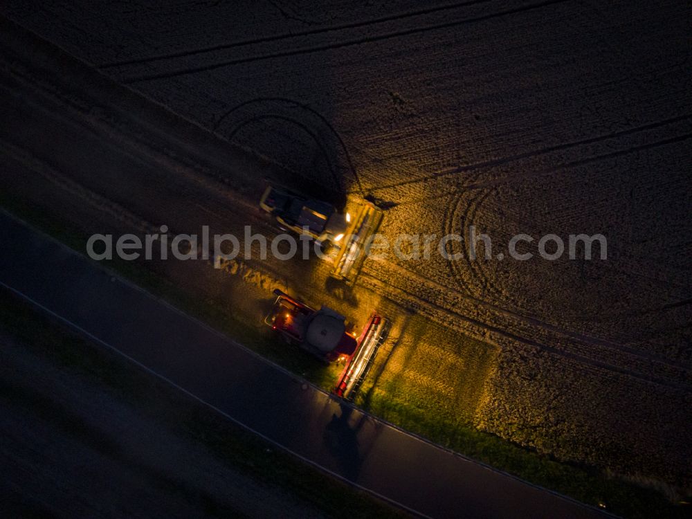 Hornschänke at night from above - Night lighting harvest use of heavy agricultural machinery - combine harvesters and harvesting vehicles on agricultural fields on street Alter Postweg in Hornschaenke in the state Saxony, Germany