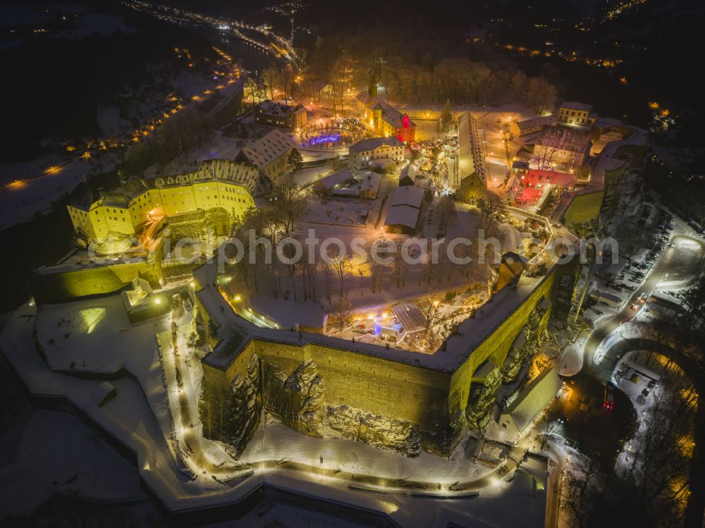 Aerial photograph at night Königstein - Night lighting the Fortress Koenigstein at the river Elbe in the county district of Saxon Switzerland East Erzgebirge in the state of Saxony. The fortress is one of the largest mountain fortresses in Europe and is located amidst the Elbe sand stone mountains on the flat top mountain of the same name