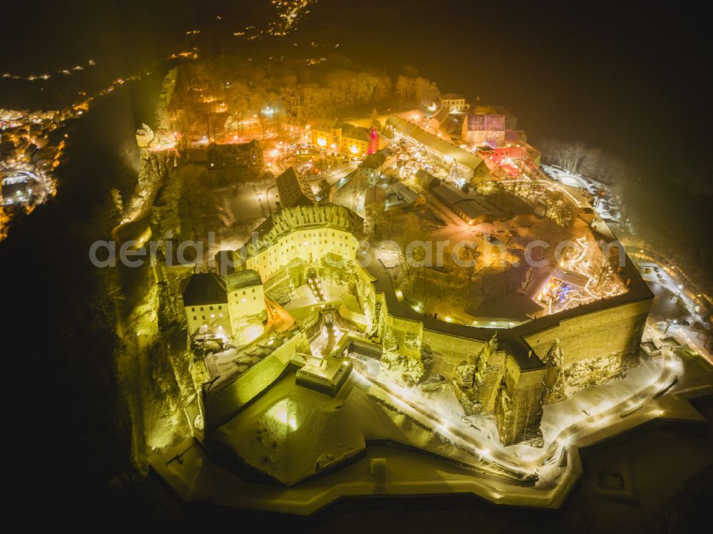 Königstein at night from the bird perspective: Night lighting the Fortress Koenigstein at the river Elbe in the county district of Saxon Switzerland East Erzgebirge in the state of Saxony. The fortress is one of the largest mountain fortresses in Europe and is located amidst the Elbe sand stone mountains on the flat top mountain of the same name