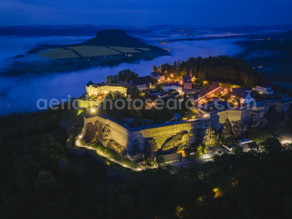 Aerial photograph at night Königstein - Night lighting the Fortress Koenigstein at the river Elbe in the county district of Saxon Switzerland East Erzgebirge in the state of Saxony. The fortress is one of the largest mountain fortresses in Europe and is located amidst the Elbe sand stone mountains on the flat top mountain of the same name