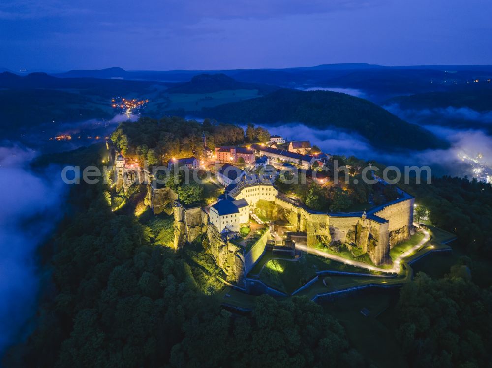 Aerial image at night Königstein - Night lighting the Fortress Koenigstein at the river Elbe in the county district of Saxon Switzerland East Erzgebirge in the state of Saxony. The fortress is one of the largest mountain fortresses in Europe and is located amidst the Elbe sand stone mountains on the flat top mountain of the same name