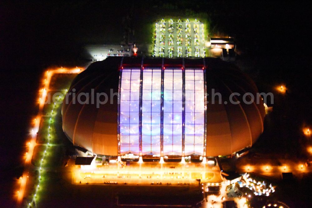 Aerial photograph at night Krausnick - Night lighting complete complex of the Theme Park Tropical Islands with air hall, outdoor pool, campsite, holiday homes and former airfield on street Tropical-Islands-Allee in Krausnick in the state of Brandenburg, Germany