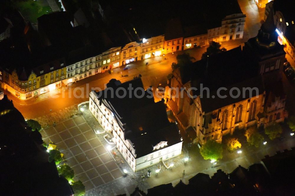 Güstrow at night from the bird perspective: Night lighting Town Hall building of the City Council at the market downtown in Guestrow in the state Mecklenburg - Western Pomerania, Germany