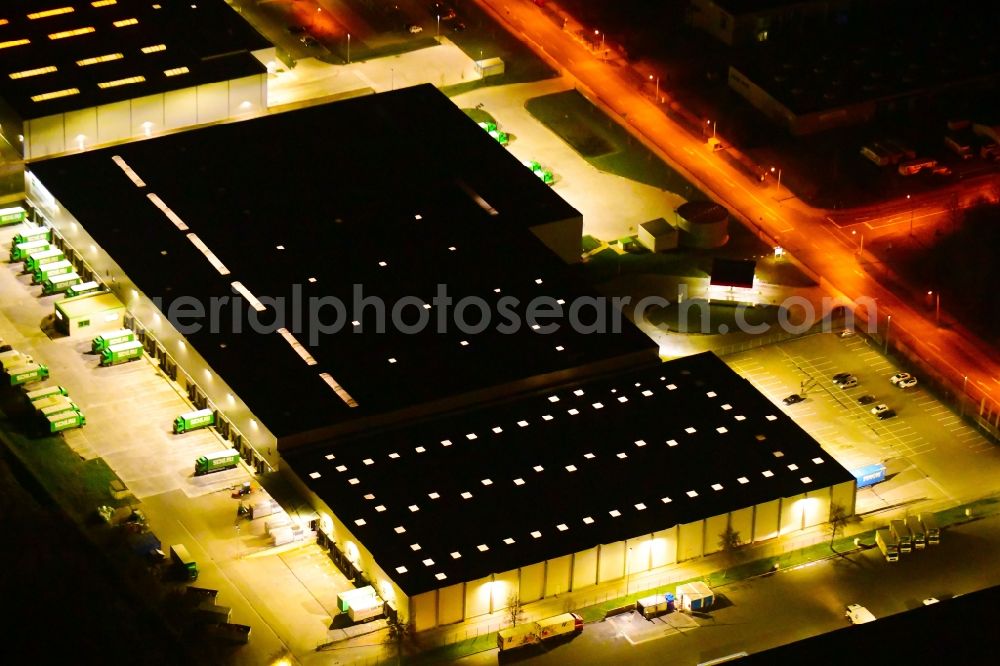 Wustermark at night from the bird perspective: Night lighting building complex and grounds of the logistics center of Brueof Schlau GmbH & Co. KG in Wustermark in the state Brandenburg, Germany