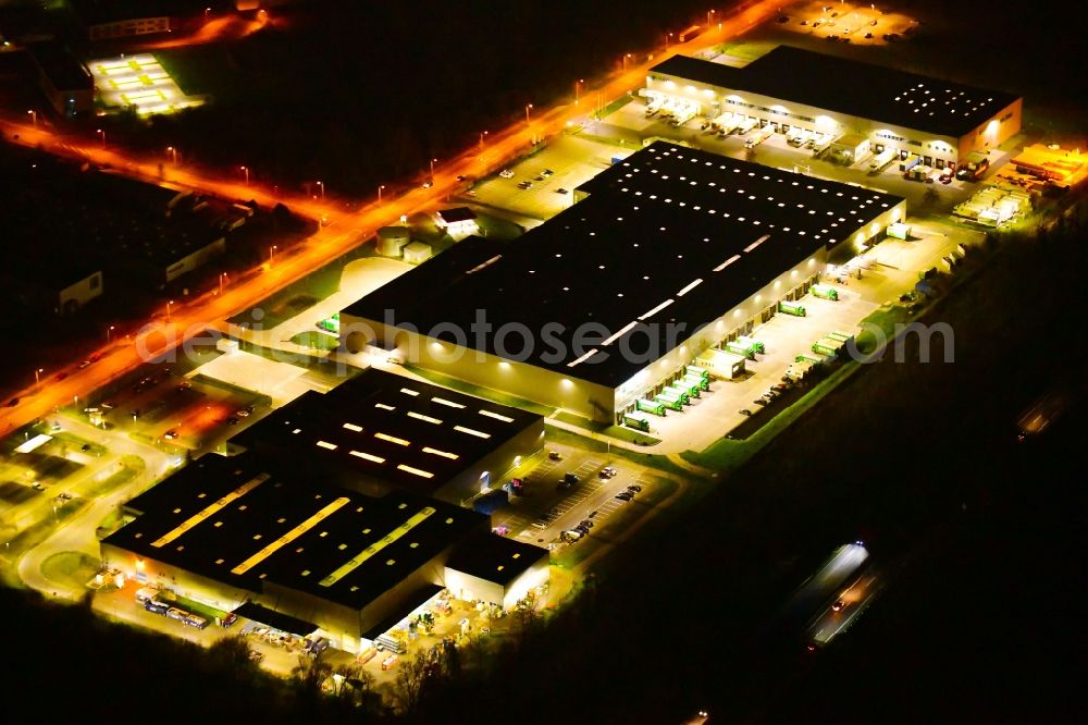 Wustermark at night from the bird perspective: Night lighting building complex and grounds of the logistics center of J&S GmbH Automotive Technology and of Brueof Schlau GmbH & Co. KG in Wustermark in the state Brandenburg, Germany