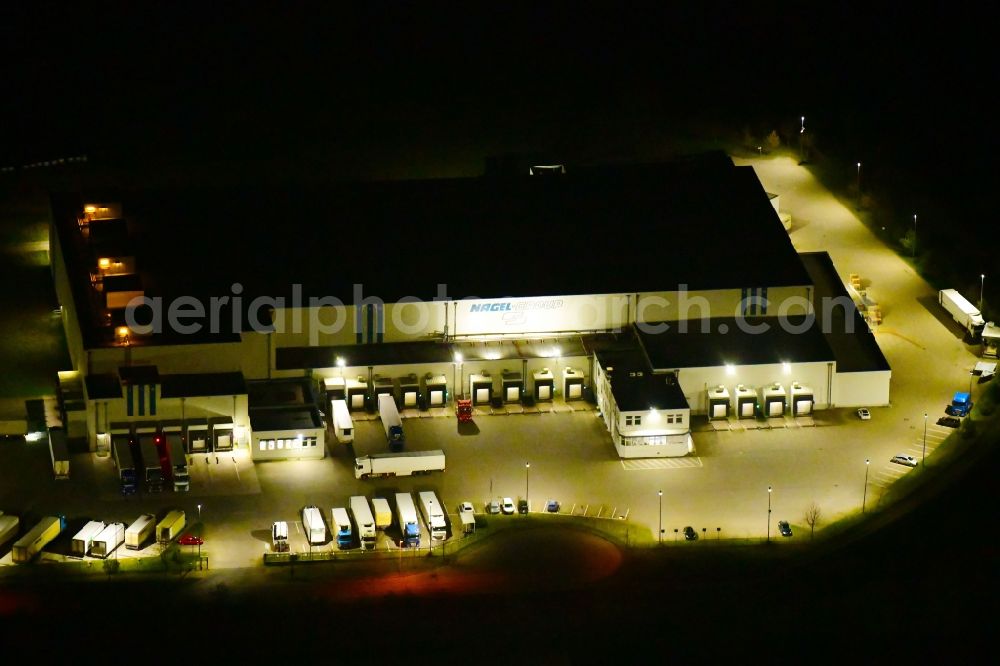 Aerial photograph at night Wustermark - Night lighting building complex and grounds of the logistics center of Kraftverkehr Nagel SE & Co. KG on Kurt-Nagel-Strasse in Wustermark in the state Brandenburg, Germany