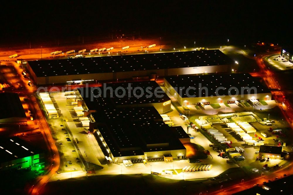 Wustermark at night from the bird perspective: Night lighting building complex and grounds of the logistics center of NETTO ApS & Co. KG in Wustermark in the state Brandenburg, Germany