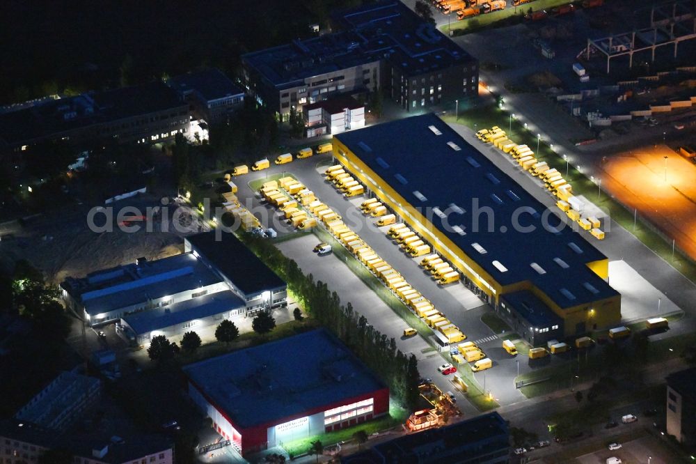 Aerial image at night Berlin - Night lighting building complex and distribution center on the site Deutsche Post - DHL Mech.ZB BRITZ on Gradestrasse in the district Bezirk Neukoelln in Berlin, Germany