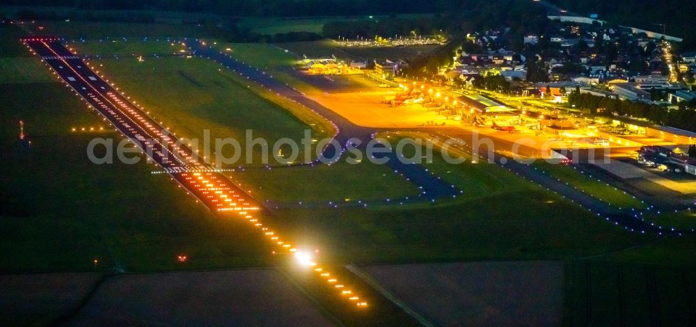 Dortmund at night from the bird perspective: Night lighting runway with hangar taxiways and terminals on the grounds of the airport in Dortmund at Ruhrgebiet in the state North Rhine-Westphalia, Germany