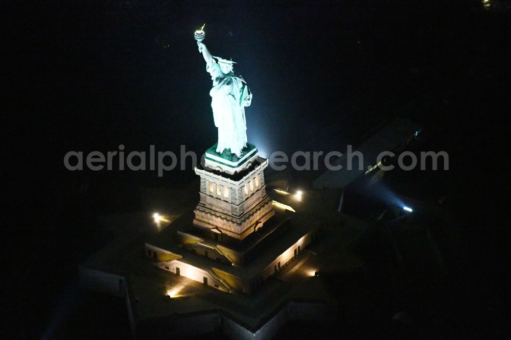 Aerial photograph at night New York - Night lighting Tourist attraction of the historic monument Freiheitsstatue - Statue of Liberty National Monument in the district Manhattan in New York in United States of America