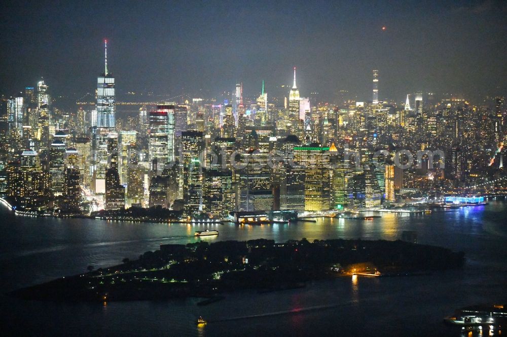 Aerial photograph at night New York - Night lighting Governors Island before the City center with the skyline in the downtown area in the district Manhattan in New York in United States of America