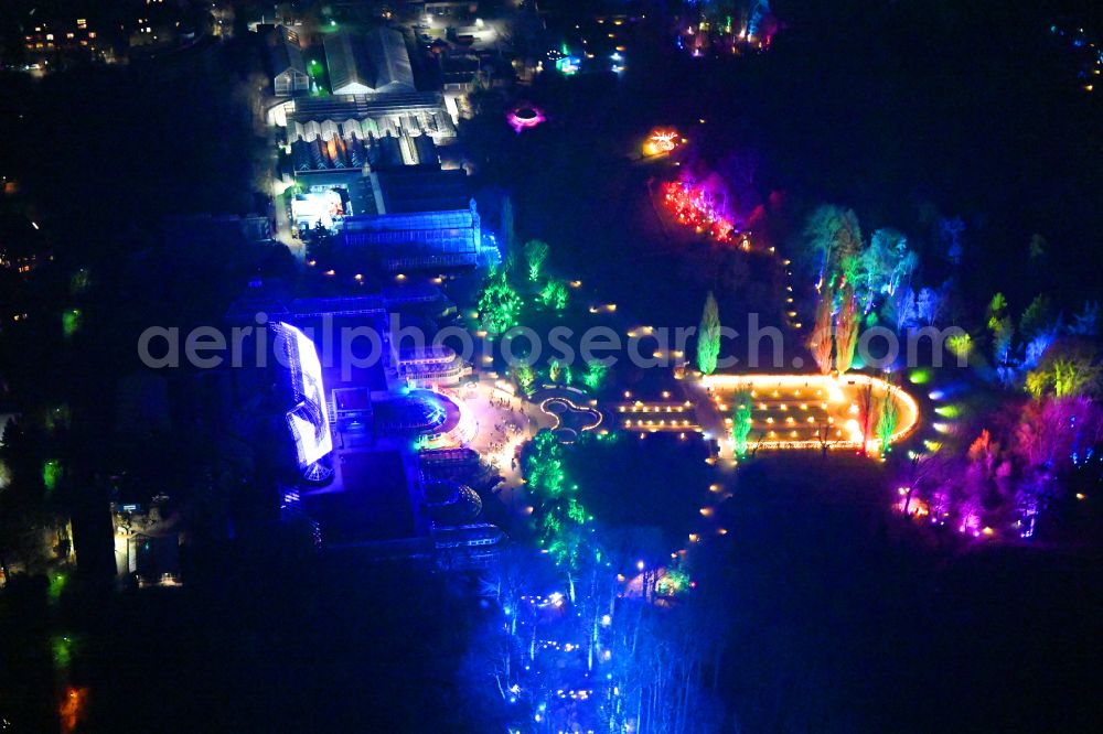 Aerial image at night Berlin - Night lighting main building and greenhouse complex of the Botanical Gardens Berlin-Dahlem in Berlin. The historical glass buildings and greenhouses are dedicated to different areas. The Large Tropical House and the Victoria-House are located in the center