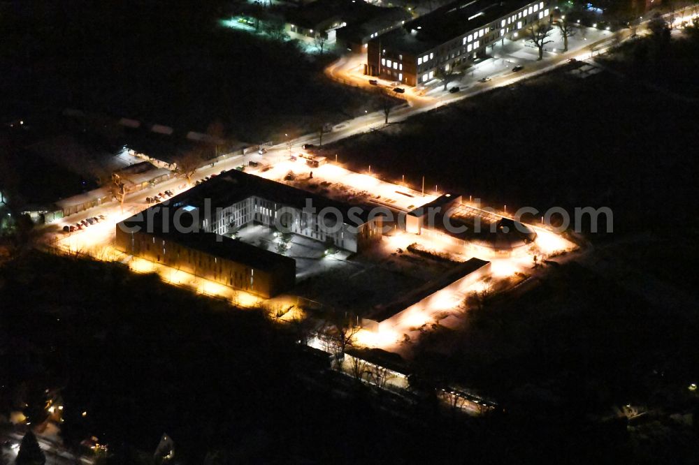 Aerial image at night Berlin - Night lighting Prison grounds and security fencing of the JVA juvenile detention center JVA of Offenen Vollzuges Berlin - Bereich Dueppel on street Robert-von-Ostertag-Strasse in the district Zehlendorf in Berlin, Germany