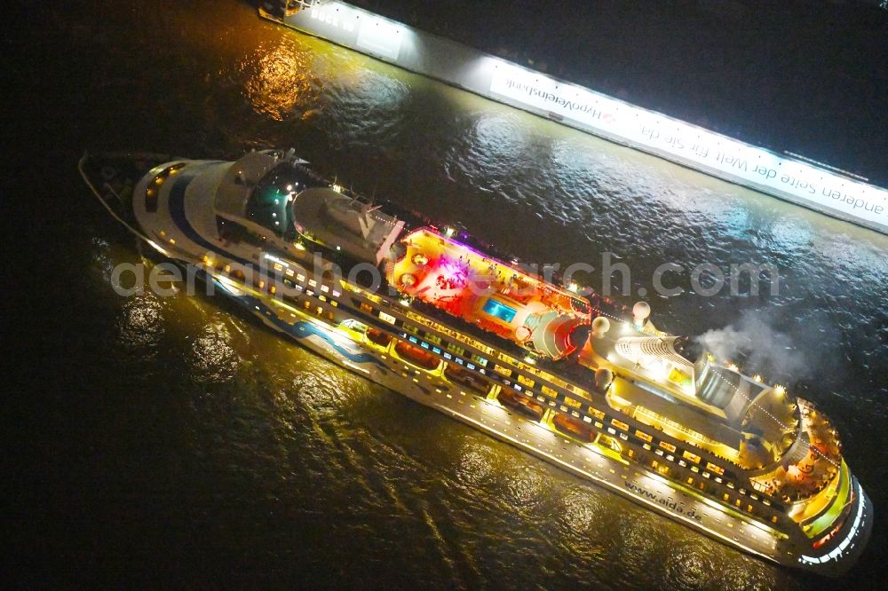 Hamburg at night from the bird perspective: Night lighting Cruise and passenger ship AIDAcara on elbe river in Hamburg, Germany