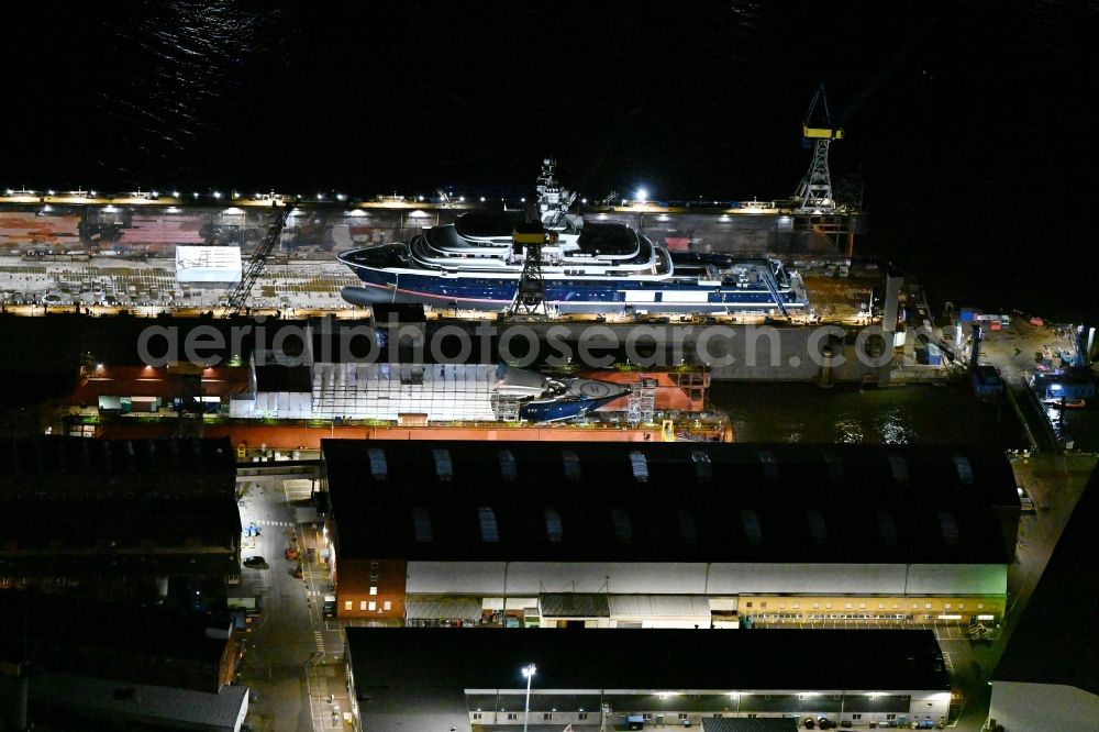 Hamburg at night from the bird perspective: Night lighting ship's hull of Luxury - yachts for maintenance, conversion and modernization in dry dock on the shipyard site in Hamburg, Germany