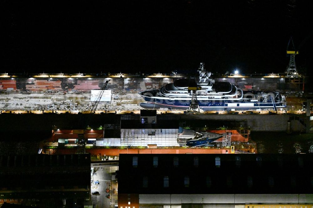 Aerial photograph at night Hamburg - Night lighting ship's hull of Luxury - yachts for maintenance, conversion and modernization in dry dock on the shipyard site in Hamburg, Germany